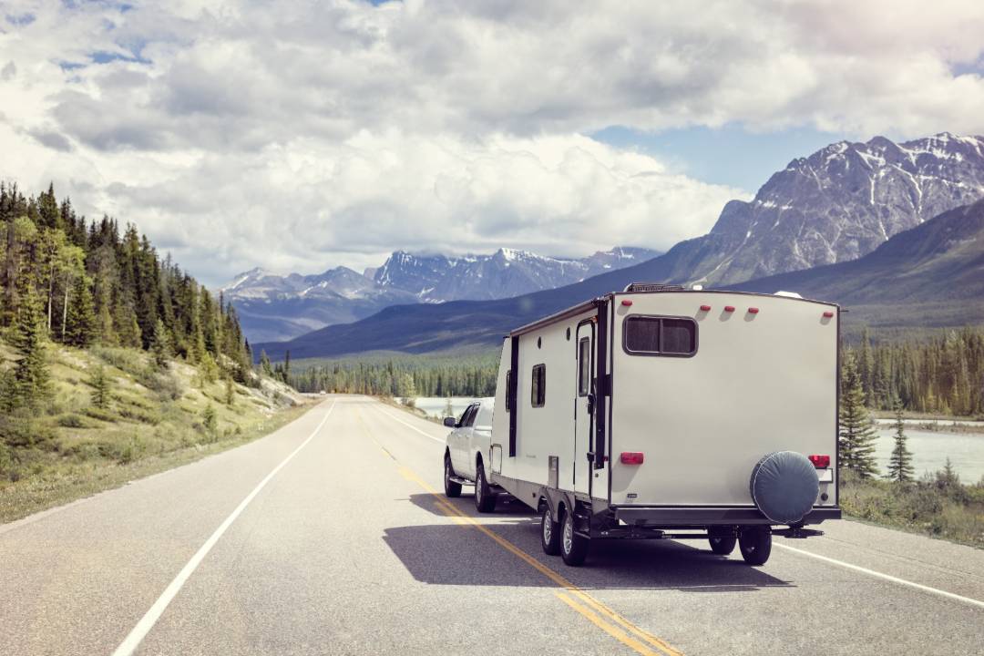 Caravan being towed on an open road with mountains in the distance