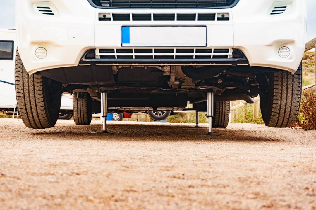White motorhome raised on workshop jacks for underside inspection