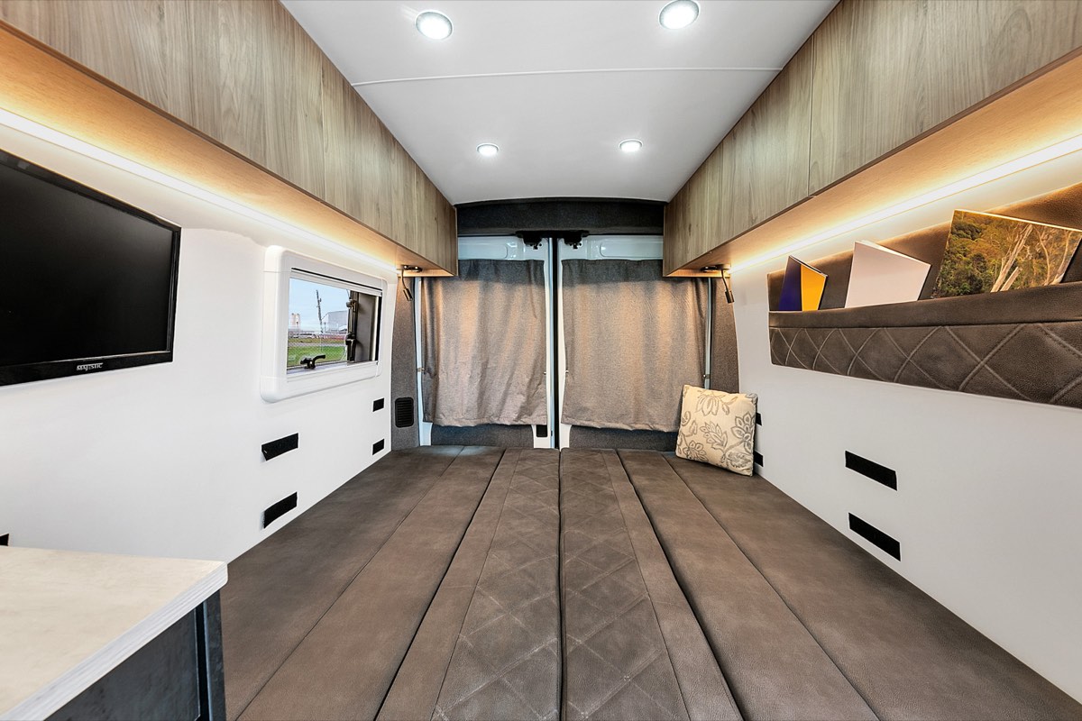 Custom campervan kitchen with fridge, microwave and cabinetry
